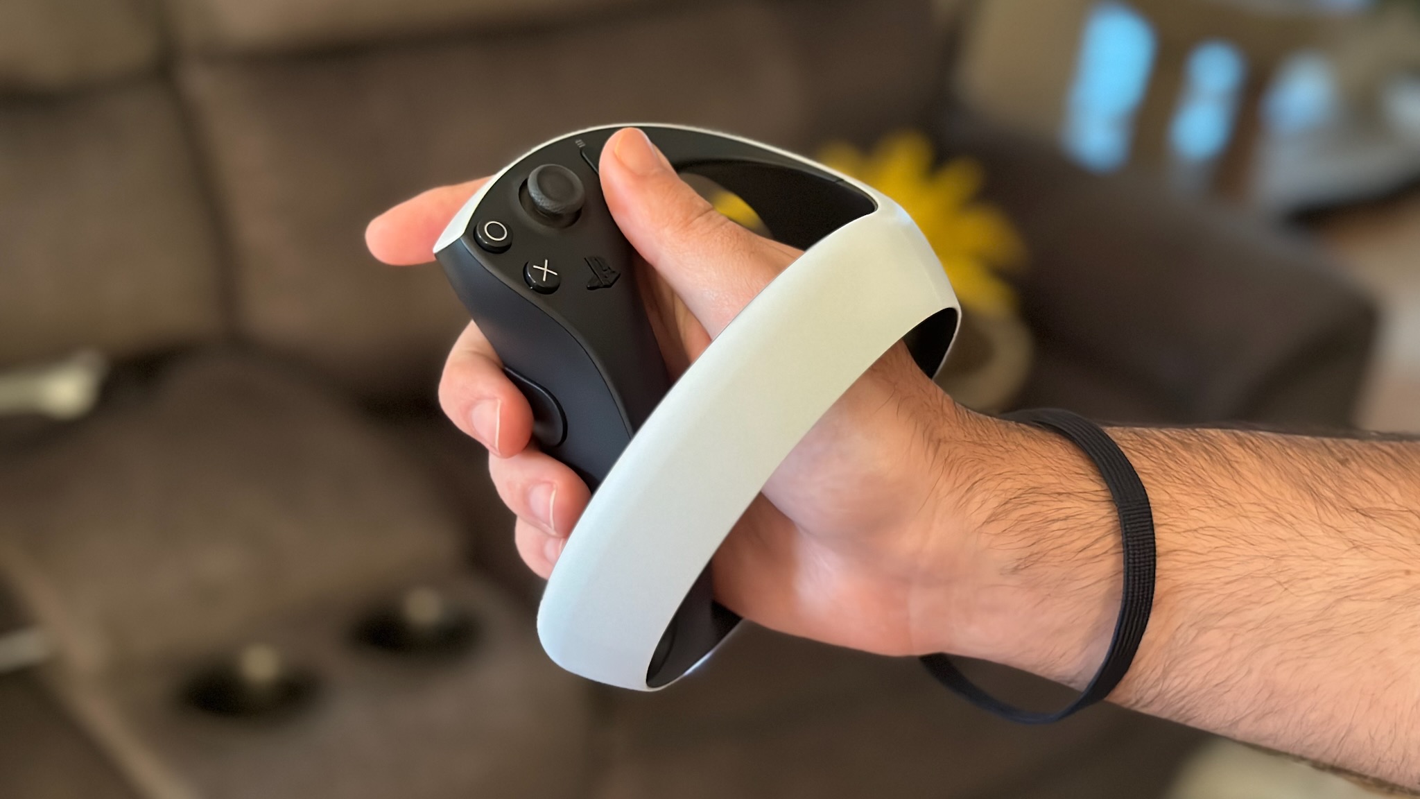 Manette Sony PS VR2 Sense tenue en main avec dragonne attachée au poignet.